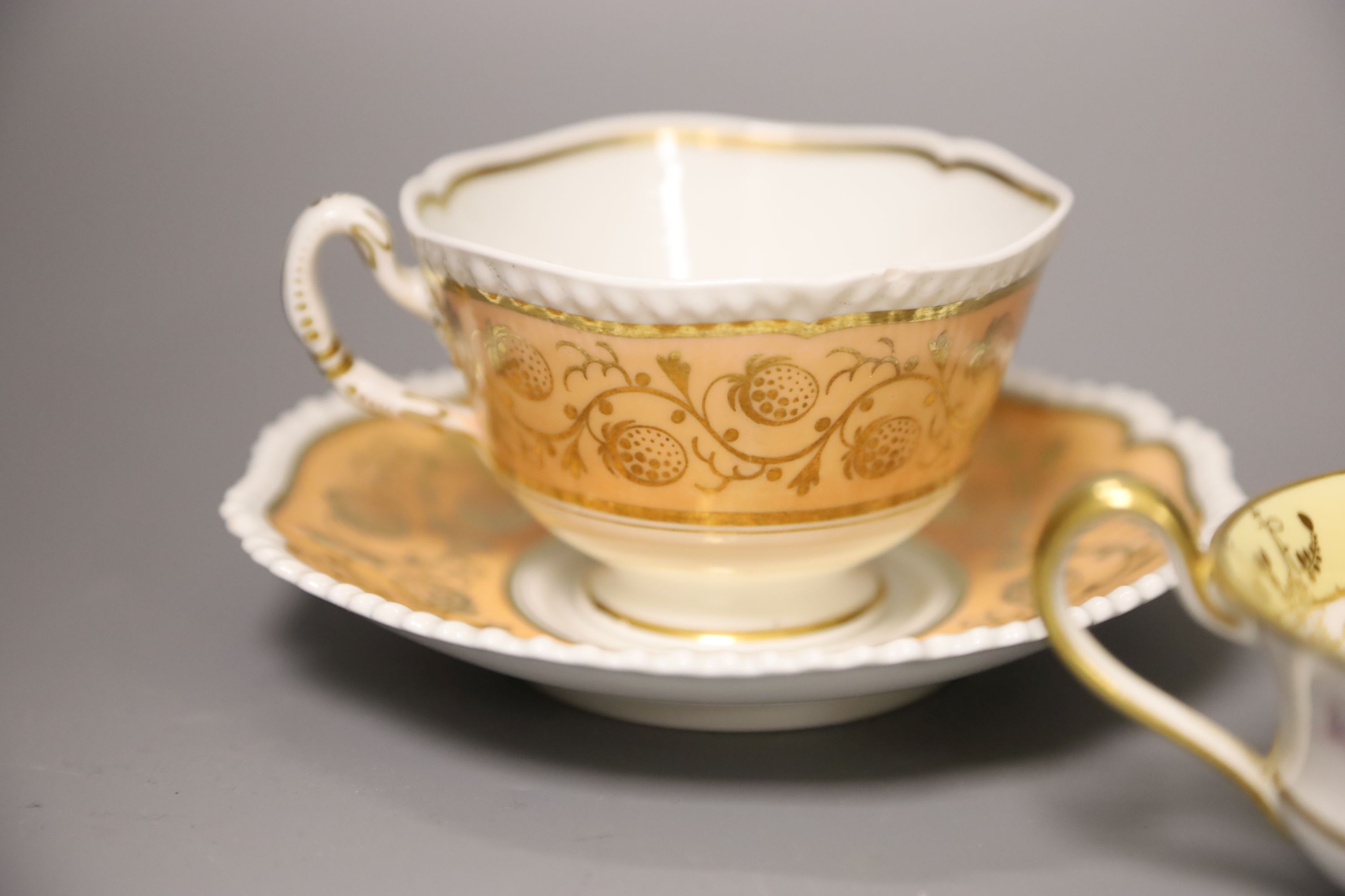 A Worcester Flight Barr teacup and saucer with gadroon border gilded with trailing berries on a salmon ground and Graingers Worcester